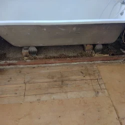 Bath with the asbestos panel removed and the floor left clean